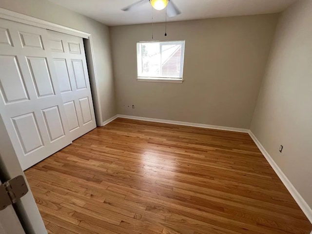 unfurnished bedroom featuring baseboards, ceiling fan, a closet, and light wood-type flooring