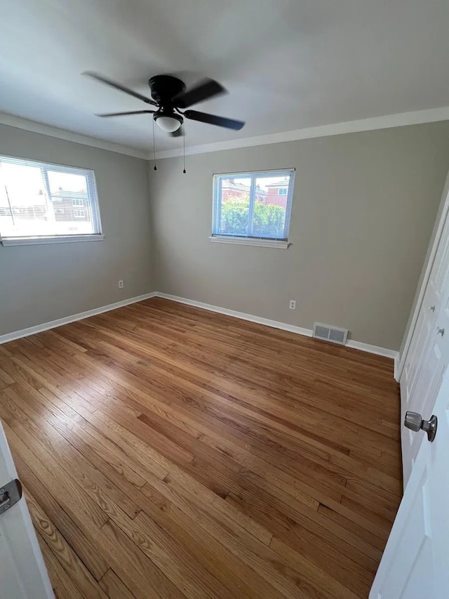 spare room with crown molding, ceiling fan, baseboards, and wood finished floors