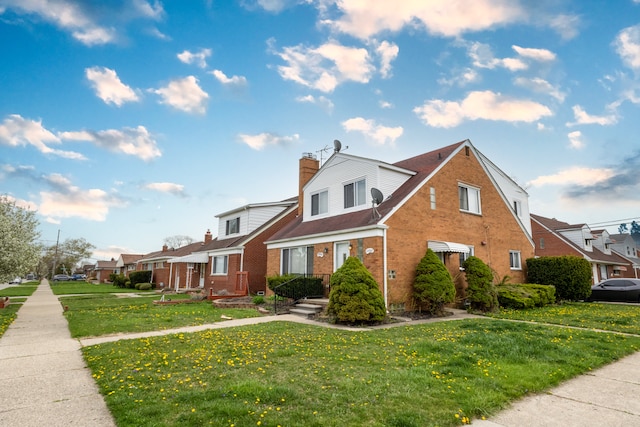 view of front of home featuring brick siding, a chimney, and a front lawn