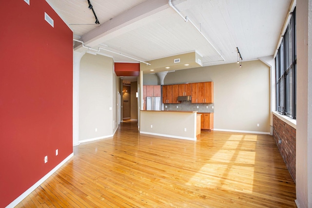 unfurnished living room with rail lighting, light wood-style flooring, and baseboards