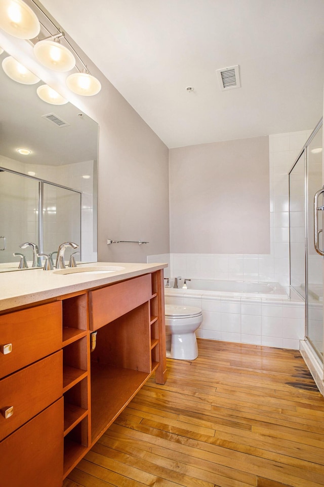 full bath with visible vents, a stall shower, wood-type flooring, a garden tub, and vanity