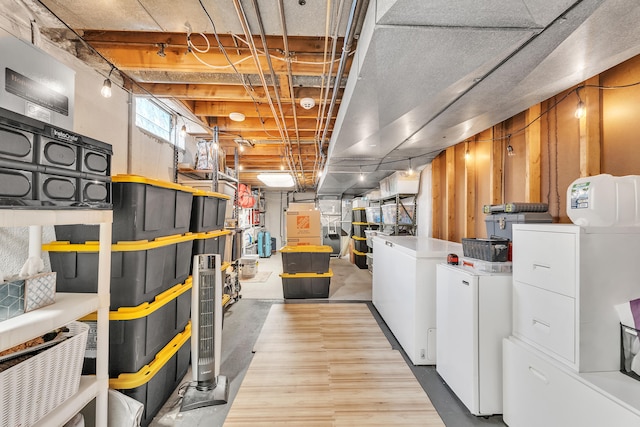 below grade area featuring wood finished floors, refrigerator, and washing machine and dryer