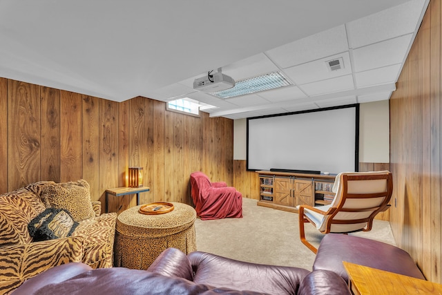 cinema room featuring visible vents, wood walls, carpet floors, and a drop ceiling