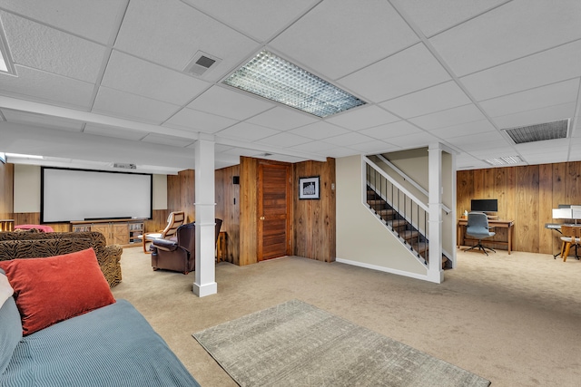 finished below grade area featuring a paneled ceiling, visible vents, wood walls, and carpet