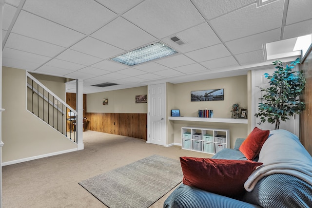 interior space featuring stairs, visible vents, wood walls, a drop ceiling, and carpet floors
