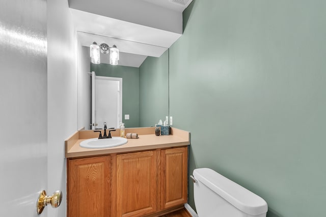 bathroom with toilet, visible vents, and vanity