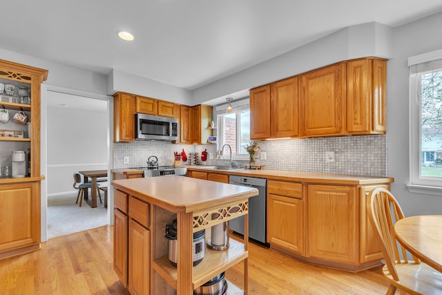 kitchen with a sink, open shelves, appliances with stainless steel finishes, and light countertops