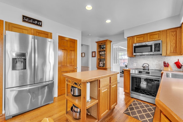 kitchen featuring stainless steel appliances, open shelves, light wood finished floors, and light countertops