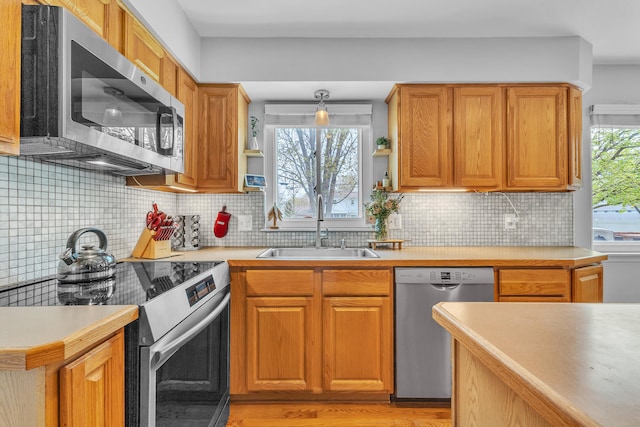 kitchen with appliances with stainless steel finishes, light wood-type flooring, light countertops, and a sink