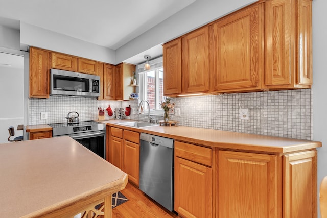 kitchen featuring stainless steel appliances, light wood finished floors, light countertops, and a sink