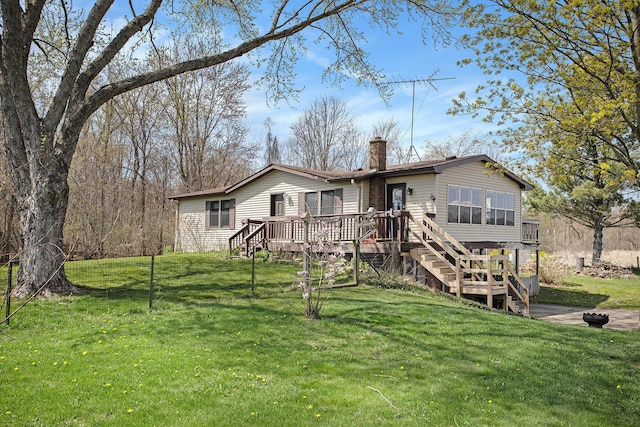 rear view of house with stairway, a deck, a yard, and a chimney