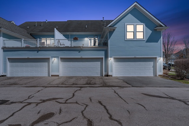 back of property at dusk featuring a balcony and driveway
