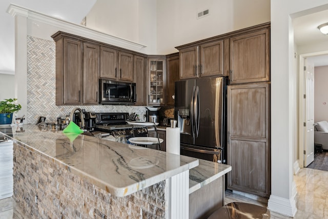kitchen featuring light stone countertops, appliances with stainless steel finishes, visible vents, and tasteful backsplash