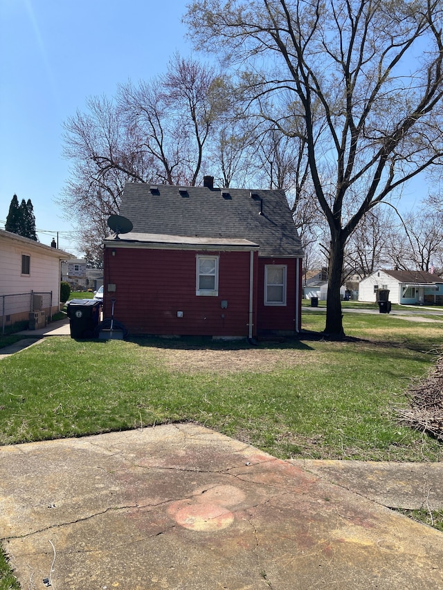 view of side of home with a lawn and a shingled roof