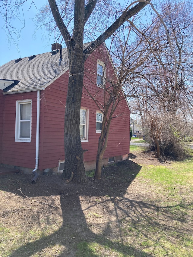 view of side of home featuring roof with shingles and a chimney
