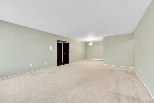 spare room with baseboards, a baseboard heating unit, and light carpet