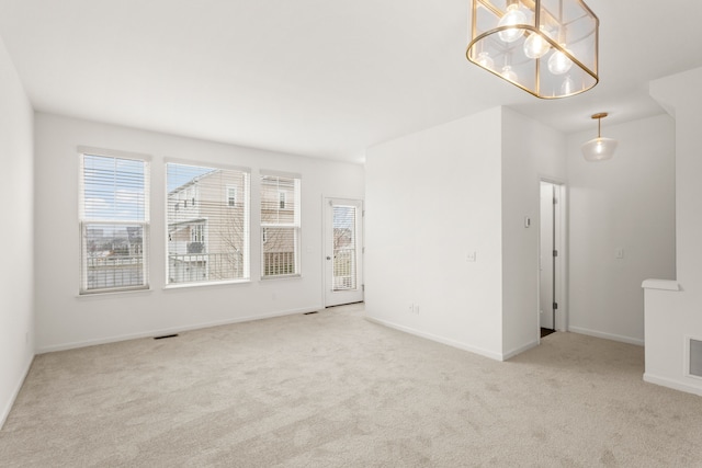 unfurnished room featuring a chandelier, baseboards, and carpet