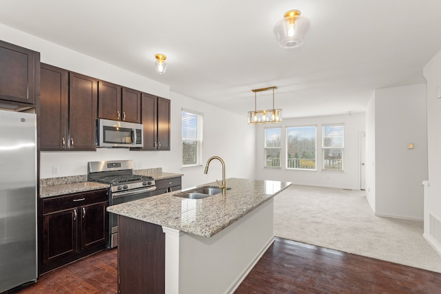 kitchen featuring appliances with stainless steel finishes, a wealth of natural light, dark brown cabinetry, and a sink