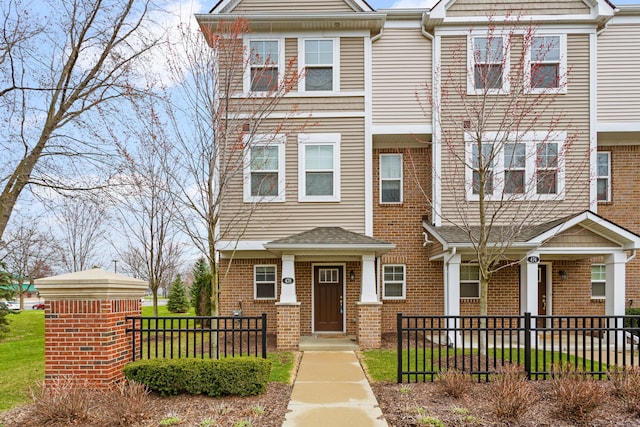 townhome / multi-family property featuring brick siding and fence