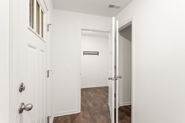 corridor with dark wood-style flooring, visible vents, and baseboards