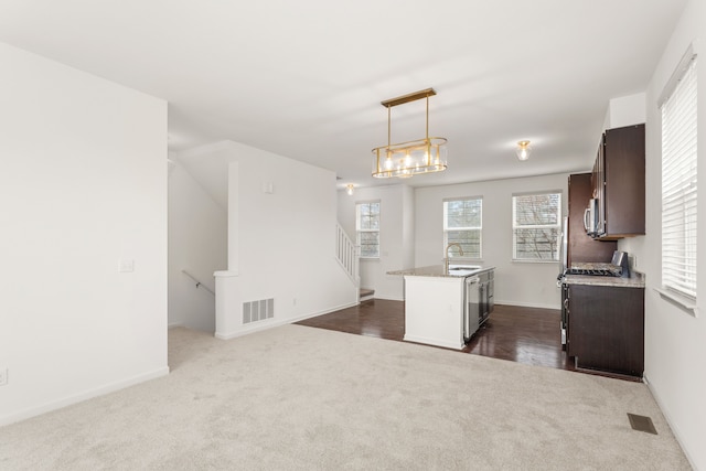 kitchen with a sink, visible vents, decorative light fixtures, dark colored carpet, and dark brown cabinets