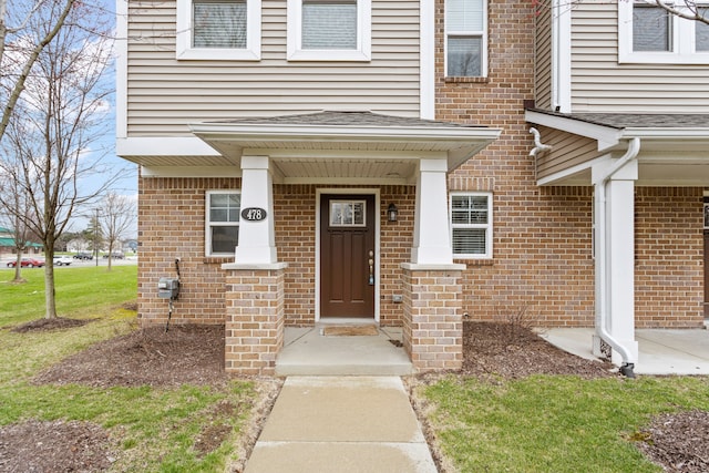 entrance to property featuring brick siding and a yard