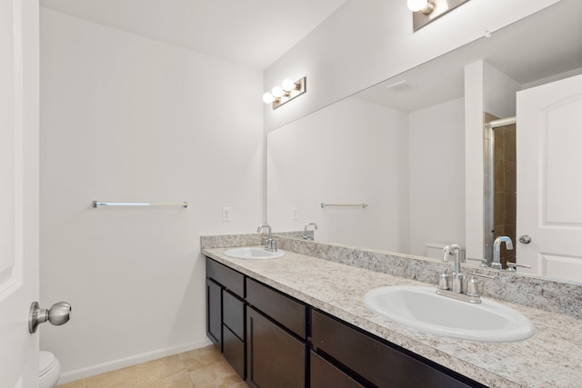 full bath featuring a shower with door, toilet, double vanity, and a sink