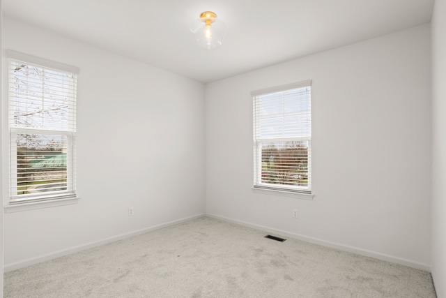 empty room with baseboards, visible vents, a healthy amount of sunlight, and carpet