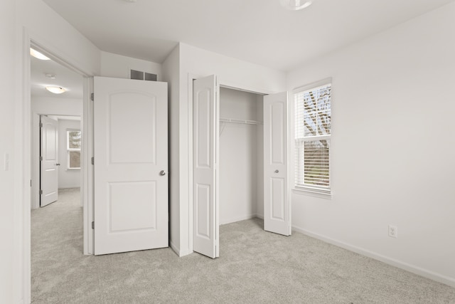 unfurnished bedroom featuring a closet, light carpet, and baseboards