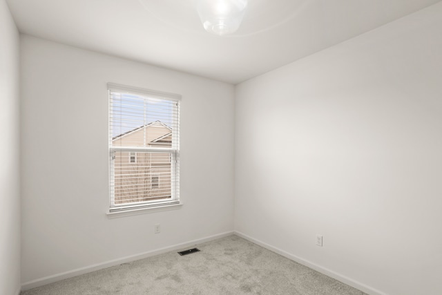carpeted spare room with visible vents and baseboards
