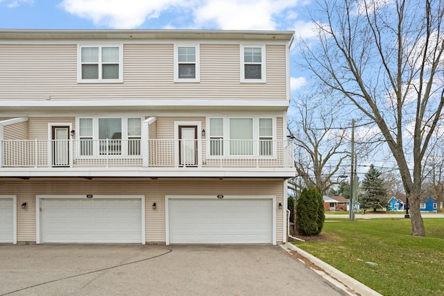 multi unit property with aphalt driveway, a front lawn, a balcony, and an attached garage