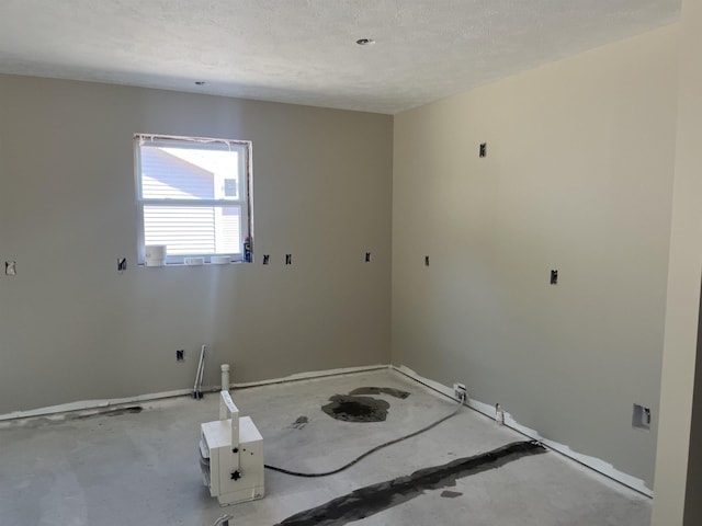 unfurnished room with baseboards and concrete flooring
