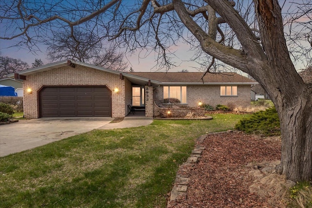 ranch-style home with a yard, an attached garage, concrete driveway, and brick siding