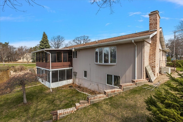 back of property with a yard, a chimney, and a sunroom