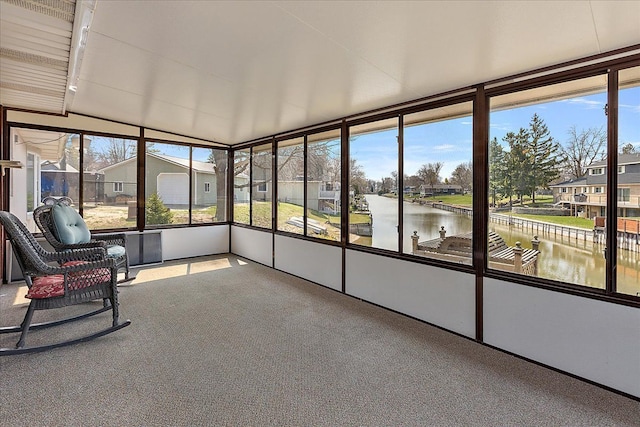 unfurnished sunroom with carpet floors, a water view, and vaulted ceiling