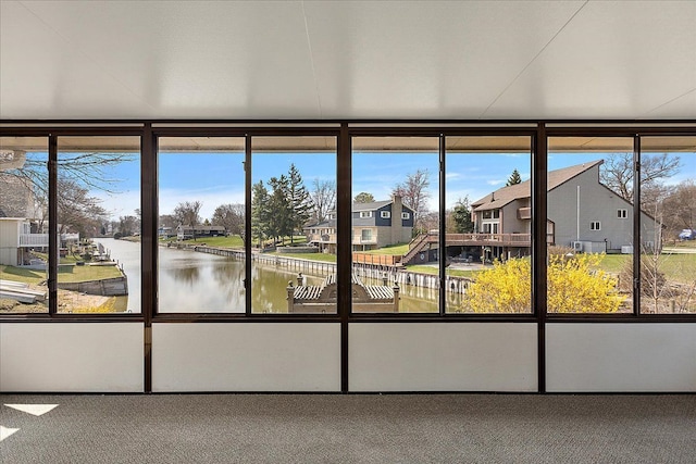 unfurnished sunroom featuring a water view and a residential view