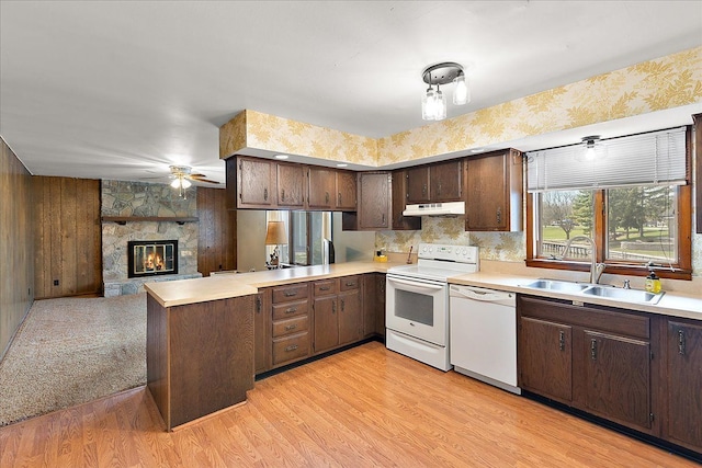 kitchen with a sink, under cabinet range hood, white appliances, and light countertops