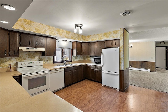 kitchen with dark brown cabinetry, a sink, white appliances, a baseboard radiator, and under cabinet range hood