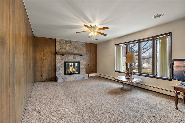 unfurnished living room featuring carpet floors, visible vents, a fireplace, wooden walls, and a ceiling fan