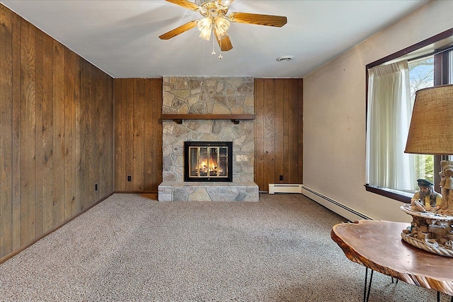living room with a ceiling fan, visible vents, a fireplace, carpet floors, and wooden walls