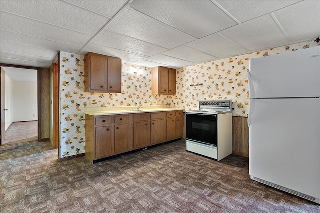 kitchen with light countertops, baseboards, wallpapered walls, and white appliances