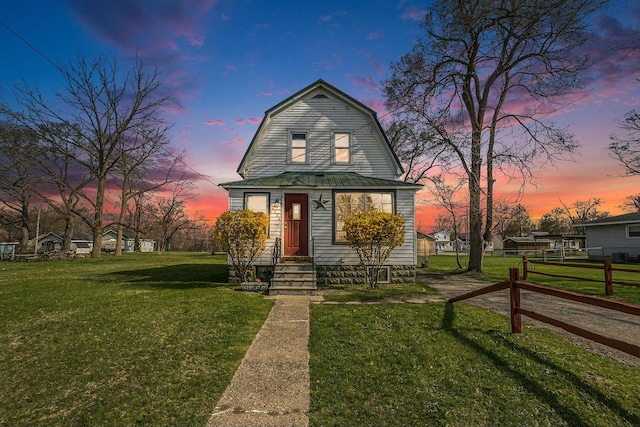 colonial inspired home featuring metal roof, a front lawn, a gambrel roof, and fence