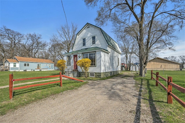 colonial inspired home with fence, a gambrel roof, an outbuilding, a shed, and a front yard