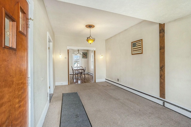 corridor with an inviting chandelier, baseboard heating, carpet floors, and baseboards
