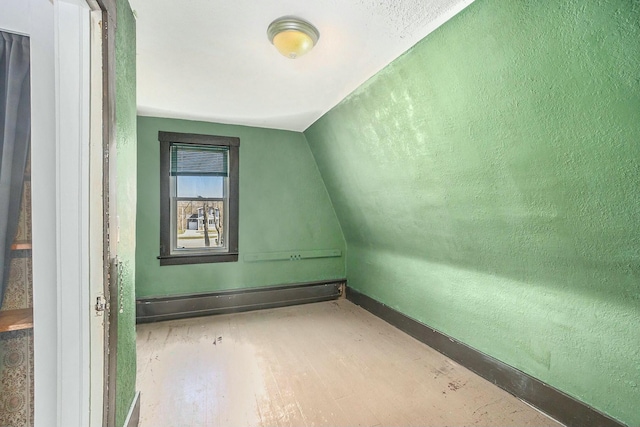 additional living space with lofted ceiling, wood finished floors, baseboard heating, and baseboards