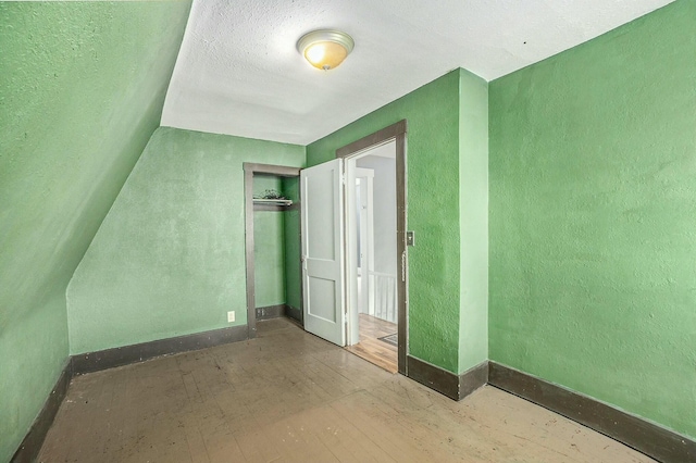 unfurnished bedroom with baseboards, hardwood / wood-style flooring, a closet, and a textured wall