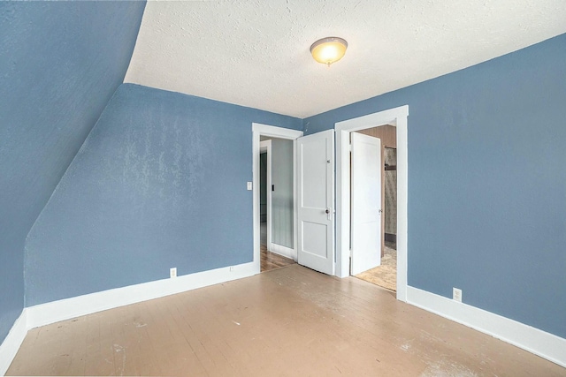 interior space with baseboards, wood finished floors, and a textured ceiling