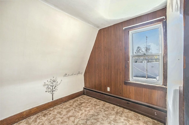 bonus room with a baseboard heating unit, carpet, baseboards, wooden walls, and lofted ceiling