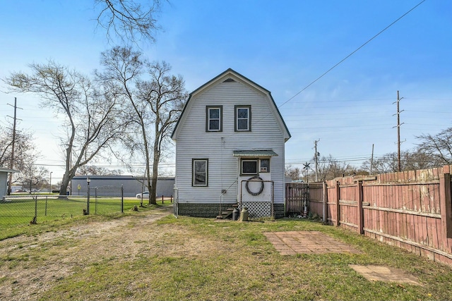 rear view of house with a lawn, a gambrel roof, and a fenced backyard