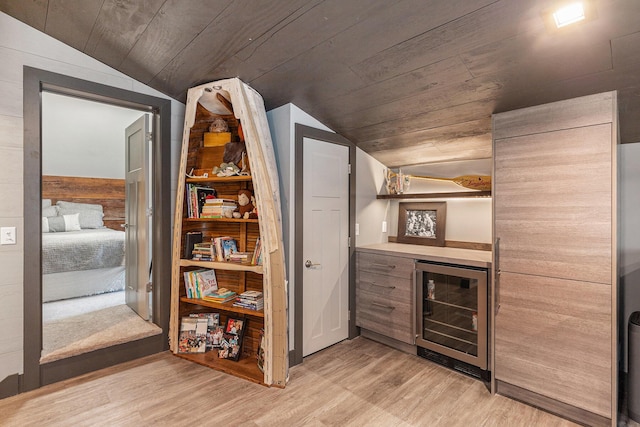 interior space featuring lofted ceiling, wood ceiling, a bar, light wood finished floors, and wine cooler
